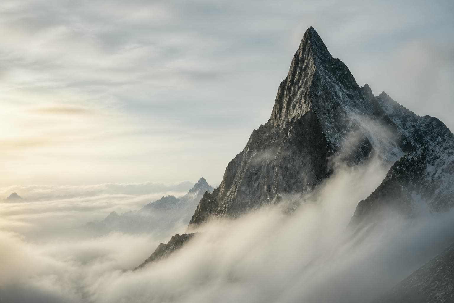 Jagged alpine peak rising above a bank of cloud